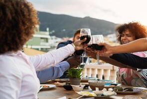 Jeune copains grillage avec rouge du vin des lunettes à dîner apéritif pendant le coucher du soleil temps - boisson et nourriture concept photo