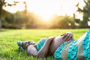 Jeune Enceinte femme mensonge sur vert herbe parc pendant le coucher du soleil temps - maternité mode de vie concept photo