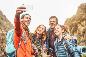 content copains prise photo selfie avec mobile téléphone intelligent caméra sur montagnes - groupe Jeune gens trekking et ayant amusement avec Nouveau La technologie les tendances - sport, randonnée, technologie et social médias concept