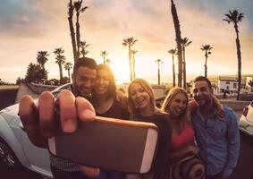 content copains permanent dans de face de convertible voiture et prise selfie avec mobile téléphone caméra - Jeune millénaire gens ayant amusement sur roadtrip dans tropical destination - Voyage et La technologie concept photo