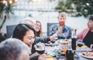 content famille applaudissement et à manger ensemble Extérieur - gens avec différent âge et l'ethnie ayant amusement à barbecue dîner fête - nourriture et boire, retraité et Jeune gens concept photo