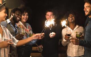 content Jeune copains ayant amusement avec cierges magiques feux d'artifice et en buvant des cocktails sur maison patio fête - jeunesse gens mode de vie et vacances concept photo