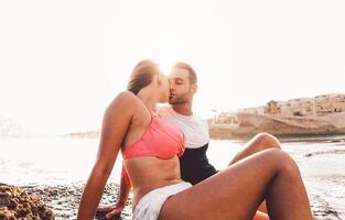 content couple embrasser sur le plage à le coucher du soleil - Jeune les amoureux ayant romantique soumissionner des moments sur été temps - gens relation et l'amour jeunesse mode de vie concept photo