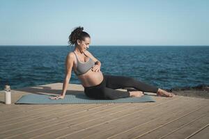 content Jeune femme caressant sa Enceinte ventre suivant le mer - santé mode de vie et maternité concept photo