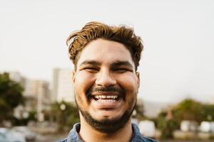 Jeune Latin homme souriant dans de face de caméra dans le ville photo