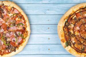 deux différent délicieux gros pizzas sur une bleu en bois Contexte photo