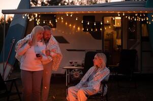 le famille est relaxant ensemble par le feu de camp près leur mobile maison. soir famille vacances photo