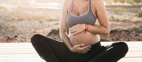 Jeune femme masser Enceinte ventre tandis que Faire yoga méditation Extérieur - santé mode de vie et maternité concept photo
