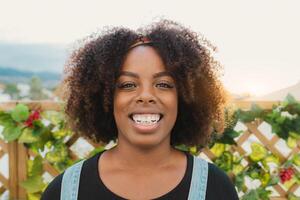 content Jeune africain fille ayant amusement souriant dans de face de caméra sur maison patio photo