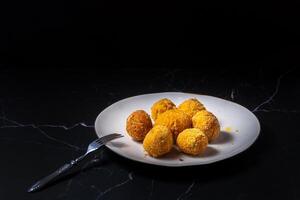 fromage des balles avec Ail et aneth à l'intérieur pour une casse-croûte dans une blanc assiette sur une noir Contexte photo