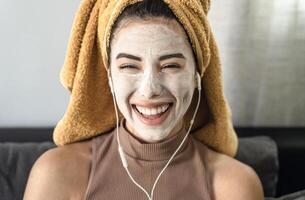 Jeune femme écoute la musique tandis que ayant peau se soucier spa journée à Accueil photo