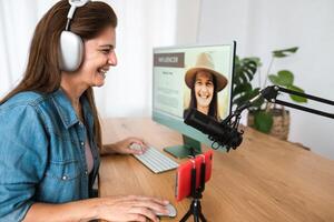 une femme portant écouteurs est séance à une bureau avec une ordinateur et microphone photo