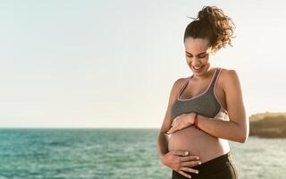 content Jeune femme caressant sa Enceinte ventre suivant le mer - santé mode de vie et maternité concept photo