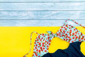 Haut vue de le maillot de bain mensonge sur une bleu en bois et Jaune background.summer vacances concept photo