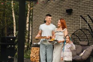 une content famille a préparé le déjeuner et volonté manger à leur maison. portrait de une famille avec nourriture dans leur mains photo