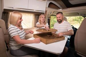 une famille de Trois est en jouant une planche Jeu tandis que séance dans une camping car photo