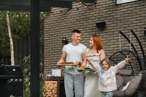 une content famille a préparé le déjeuner et volonté manger à leur maison. portrait de une famille avec nourriture dans leur mains photo