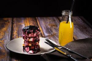 frit gâteaux au fromage avec myrtille confiture et acide crème sur une assiette avec Orange jus dans une bouteille photo