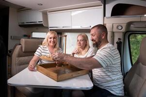 une famille de Trois est en jouant une planche Jeu tandis que séance dans une camping car photo