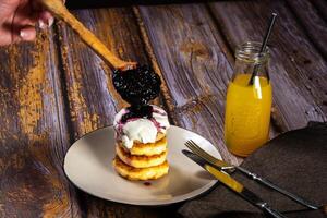 gâteaux au fromage avec myrtille confiture et acide crème sur une assiette avec Orange jus dans une bouteille photo