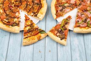 deux différent délicieux gros pizzas sur une bleu en bois Contexte photo
