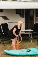 une femme gonfle une sup-board pour nager près sa camping car photo