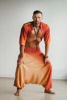 une homme dans un Orange costume Est-ce que yoga par en mouvement le sien abdominal muscles dans le salle de sport. le concept de santé photo