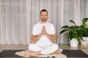 une homme dans blanc tenue de sport est Faire yoga avec une aptitude chambre. le concept de une en bonne santé mode de vie photo