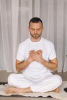 une homme dans blanc tenue de sport est Faire yoga avec une aptitude chambre. le concept de une en bonne santé mode de vie photo