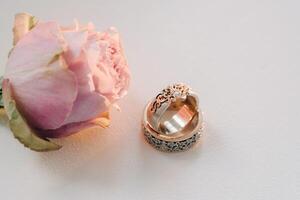 designer mariage anneaux mensonge sur le surface avec une Rose. deux mariage anneaux photo