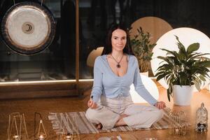 une femme est séance dans une lotus position avec parfumé bougies dans sa mains dans le Gym photo