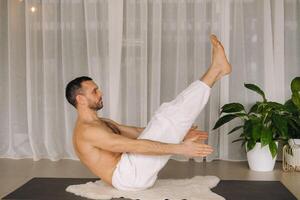 une homme avec une nu torse Est-ce que yoga dans une aptitude chambre. le concept de une en bonne santé mode de vie photo