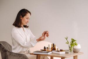 le aromathérapeute fille est séance dans sa bureau. là sont essentiel huiles sur le table photo