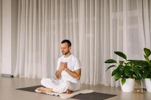 une homme dans blanc tenue de sport est Faire yoga avec une aptitude chambre. le concept de une en bonne santé mode de vie photo