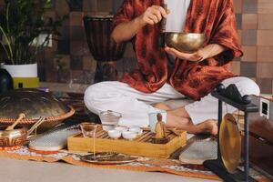Tibétain en chantant bol dans le mains de une homme pendant une thé la cérémonie photo