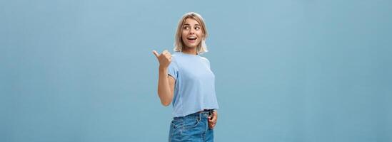 charmant sociable et amical élégant femelle avec blond cheveux tournant droite à spectacle façon ou tandis que discuter quelque chose parlant avec détendu insouciant Regardez posant plus de bleu Contexte dans branché tenue photo