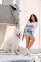 une content femme avec une gros blanc chien sur une blanc yacht dans le mer photo