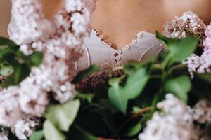 magnifique fille avec lilas fleurs dans sa mains. une fille avec lilas fleurs dans le printemps à maison. une fille avec longue cheveux et lilas dans sa mains photo