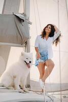 une content femme avec une gros blanc chien sur une blanc yacht dans le mer photo