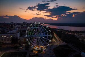 magnifique le coucher du soleil plus de le ville avec une éclairé ferris roue. photo