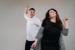 une homme oscillations le sien poing à une battu femme permanent sur une gris Contexte. national la violence photo