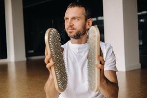 une homme détient dans le sien mains planches avec ongles pour yoga Des classes photo