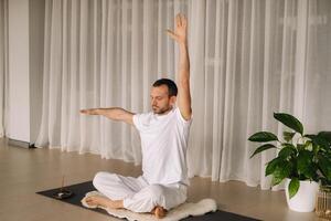 une homme dans blanc tenue de sport est Faire yoga avec une aptitude chambre. le concept de une en bonne santé mode de vie photo