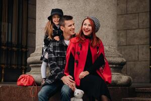 une élégant famille de Trois balades par le l'automne ville posant pour une photographe . papa, maman et fille dans le l'automne ville photo