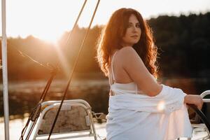 sexy femme dans une blanc chemise jouit le le coucher du soleil sur sa privé blanc yacht photo