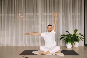 une homme dans blanc tenue de sport est Faire yoga avec une aptitude chambre. le concept de une en bonne santé mode de vie photo