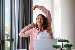 Jeune femme travail sur portable. affaires femme occupé travail sur portable étirement. femme d'affaires séance à brillant moderne travail station photo