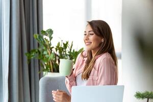 Jeune affaires femmes dans le Bureau en buvant café et à la recherche par une fenêtre photo