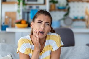 portrait de malheureux Jeune femme Souffrance de mal aux dents à maison. soins de santé, dentaire santé et problème concept. photo