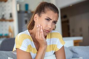 portrait de malheureux Jeune femme Souffrance de mal aux dents à maison. soins de santé, dentaire santé et problème concept. photo